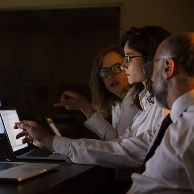 Equipo de trabajo revisando información en conjunto frente a un computador.
